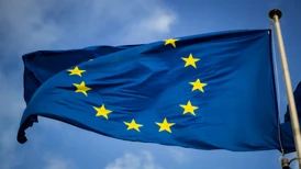 EUs blå och gula stjärnflagga med blå himmel i bakgrunden