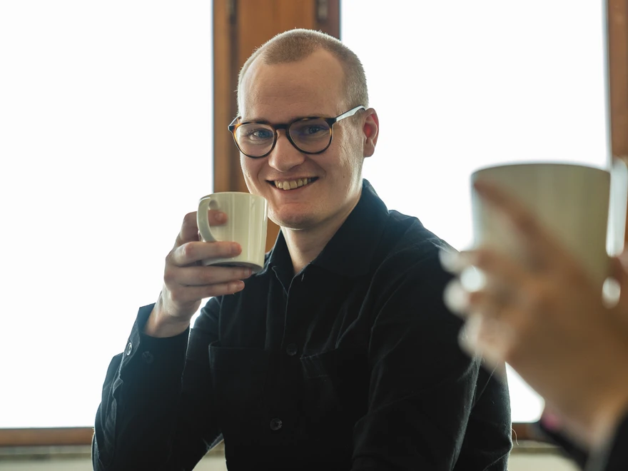 En medarbetare på Epinova dricker kaffe och är glad