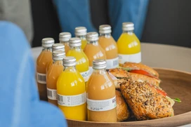 Flaskor med juice och smörgåsar med frön på ett runt träfat, 