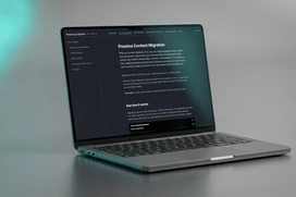 Modern laptop som visar en mörkt tema webbplats om innehållsmigrering på ett rent grått skrivbord