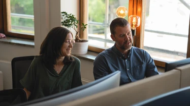 Två personer samtalar vid en datorskäm