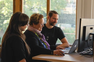 Tre kollegor vid ett skrivbord framför en datorskärm