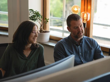 two persons talking infront of computer
