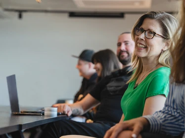 Glada personer i ett konferensrum sittandes vid ett konferensbord