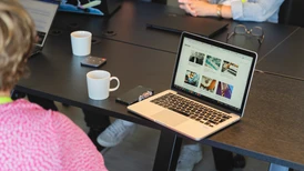 Konferensrum med en bärbar dator på ett bord och ryggen av en kvinna