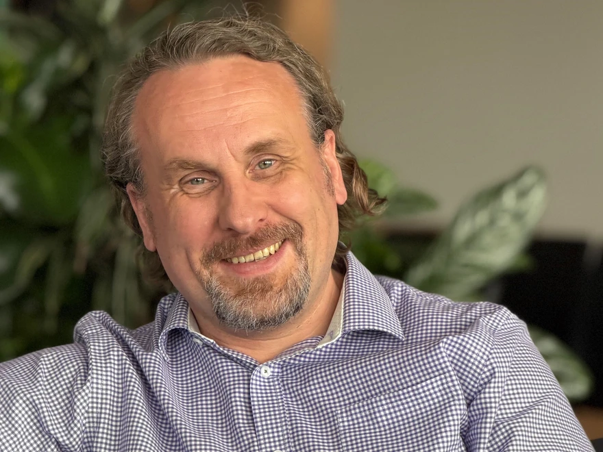 Portrait of a man on a couch indoors with blurred plants in the background