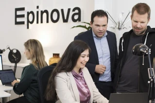 Personer arbetar vid datorer på ett kontor med Epinova-logotypen i bakgrunden
