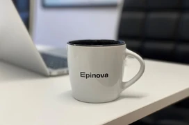 Vit mugg med texten "Epinova" på ett skrivbord bredvid en bärbar dator
