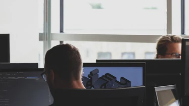 Kontorsmiljö med flera personer som arbetar framför datorskärmar