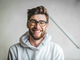 Leende man med glasögon och skäggklädd i vit hoodie